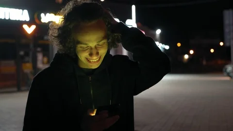 Man's face illuminated of multicolor  light by screen phone outdoors at night, 4 Vidéo 95624521
