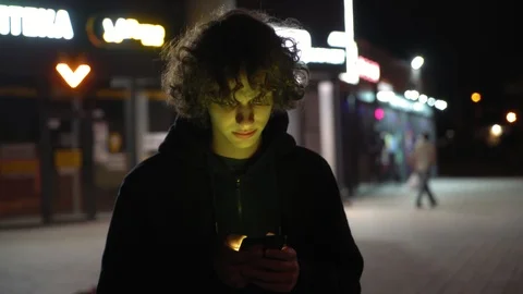 Man's face illuminated of multicolor  light by screen phone outdoors at night, 3 Video stock 95624569