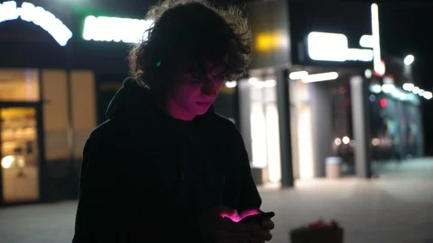 Man's face illuminated of multicolor  light by screen phone outdoors at night, 2 Vidéo 95624602