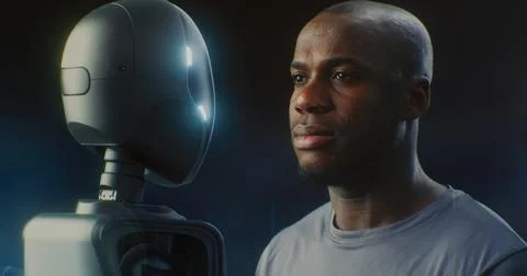 Mans Face Next Sleek, Dark Robot, Both Gazing With Neutral Expression Stock Photos