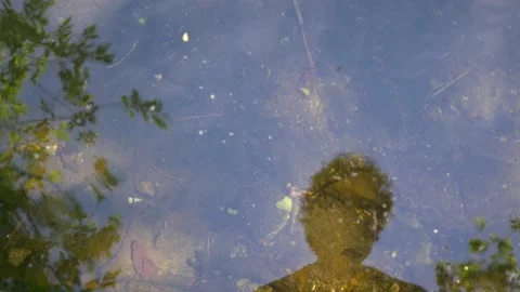 Man's face is reflected in the water of a pond. 库存影片 154942984