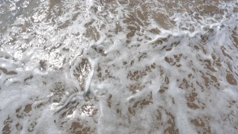 Man's feet washed by ocean waves and buries them in the sand. Point of view of Stock Footage 86233248