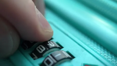 Man's finger dials the code on the lock of a turquoise travel suitcase. Closeup Stock Footage 249015898