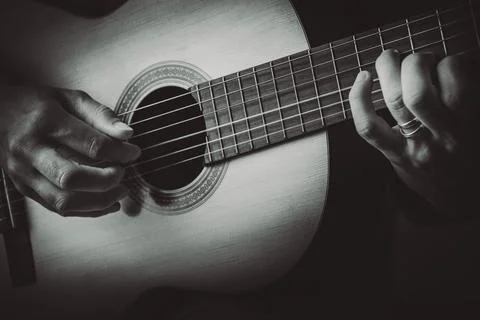 Man's finger playing strings of guitar Stock Photos