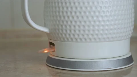 A man's finger pressing a button on an white electric kettle to boil water Stock Footage 197682126