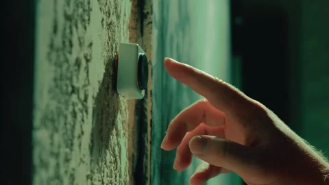 Man's finger pressing a small white doorbell button on a textured wall Stock Footage 336337778
