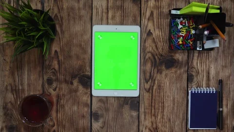 A man's finger scrolling on the green touchscreen. A tablet is on the wooden Stock Footage 105784446