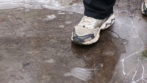 Man's foot crushing ice on puddle in winter Video stock 82318548