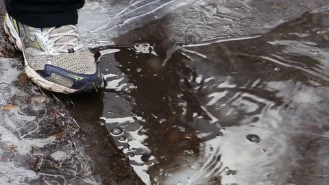 Man's foot crushing ice on puddle in winter Video stock 82318685