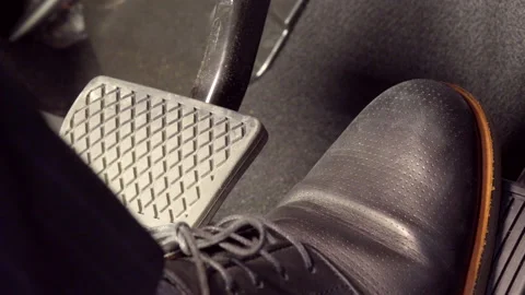 A man's foot pressing accelerator, suddenly, hits the brake, wearing black Stock Footage 135611329