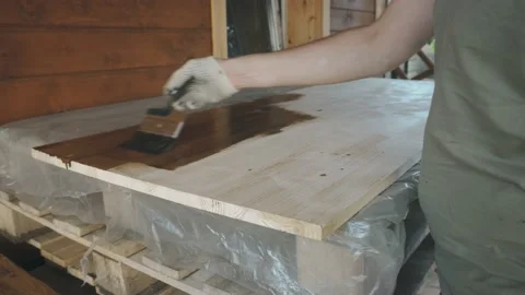 A man's gloved hand gently covers the wooden tabletop with a brush 库存影片 145260502