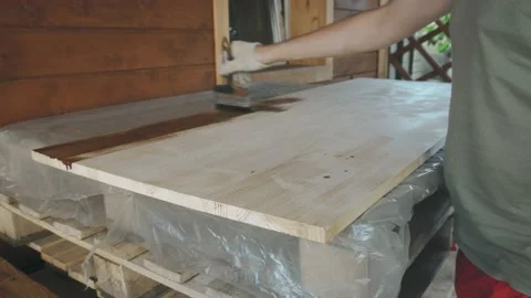 A man's gloved hand gently covers the wooden tabletop with a brush 库存影片 145260685