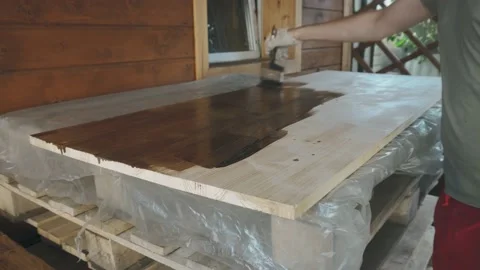 A man's gloved hand gently covers the wooden tabletop with a brush Video stock 145260789