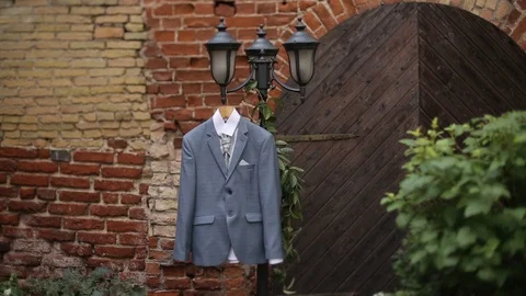 A man's gray jacket suit hanging in the yard hangs on a hanger before the groom Stock Footage 93841140