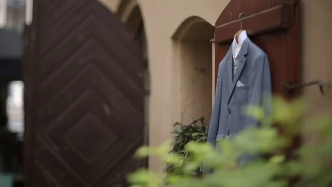 A man's gray jacket suit hanging in the yard hangs on a hanger before the groom Video stock 93841198