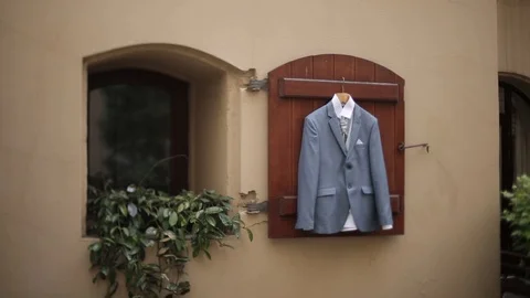 A man's gray jacket suit hanging in the yard hangs on a hanger before the groom Video stock 93841478