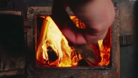 Man's Hand Adding Firewood to Rusty Stove - Feeding the Fire Stock Footage 327991229