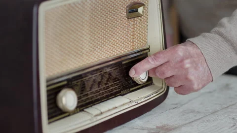Man's hand adjusting knobs on a vintage radio in a homely setting Video stock 274662034