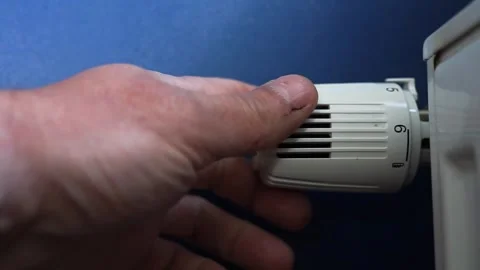 Mans hand adjusting the room temperature on white radiator Stock-Footage 310487313