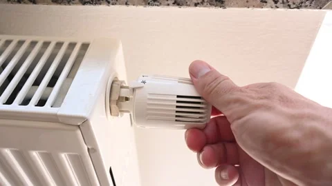 Man's hand adjusting the temperature on valve of a radiator at home. Stock Footage 262017490