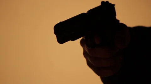 Man's Hand Aims a 1911 .45 Caliber Pistol in a dark room - Silhouette Stock Footage 106941730