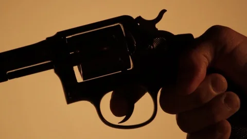 Man's Hand Aims and Points a Revolver in a dark room - Silhouette Stock Footage 106941027