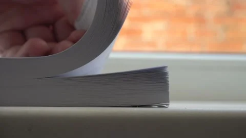 Man's hand around the corner quickly flips a thick book Stock Footage 148957848