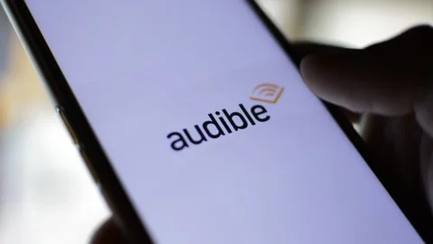 Man's hand with audible book reader logo icon on his phone. audible logo Vidéo 200872053