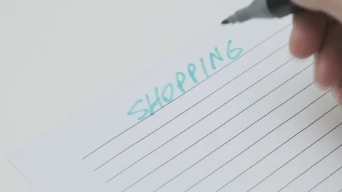 Man's hand with blue felt-tip pen writes phrase shopping list on paper 스톡 동영상 265880356