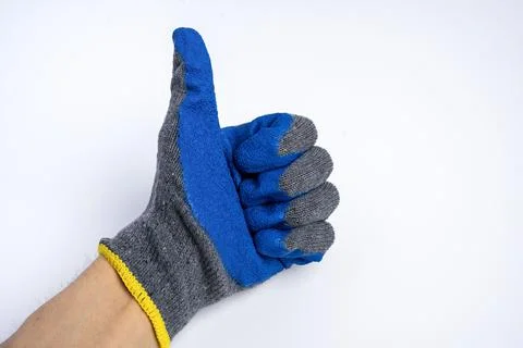 A man's hand in blue rubberized work gloves shows a thumbs up on a blue backg Stock Photos