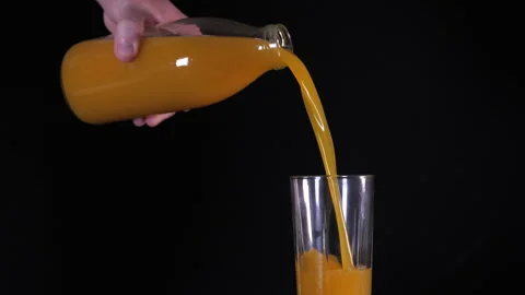 Man's hand with bottle pours bright yellow orange juice into glass Stock Footage 144555827