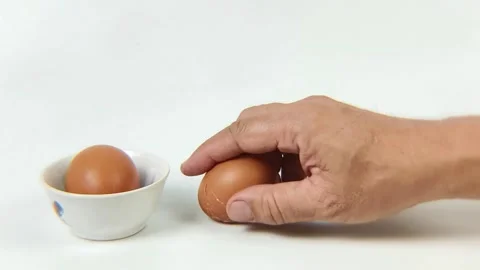 A man's hand is breaking the shell of a boiled egg by tapping it on the tab.. Stock Footage 338330295