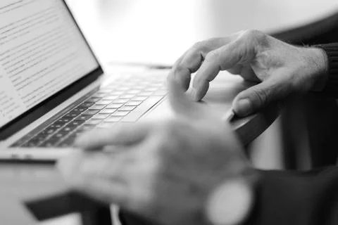 Man's hand brush on the notebook cursor control button while working with inf Stock Photos