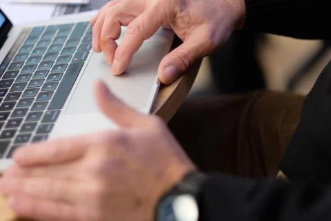 Man's hand brush on the notebook cursor control button while working with inf Stock Photos