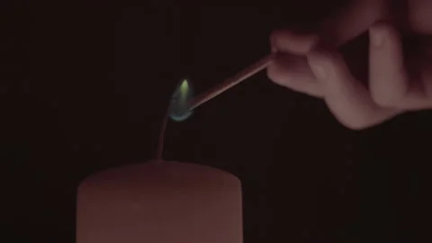 A man's hand with a burning match, lights the wick of a candle, close up, dark Stock Footage 236419715