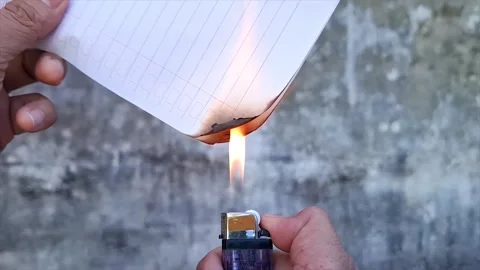 A Man's Hand Is Burning Paper Using A Purple Plastic Lighter Stock Footage 292588892