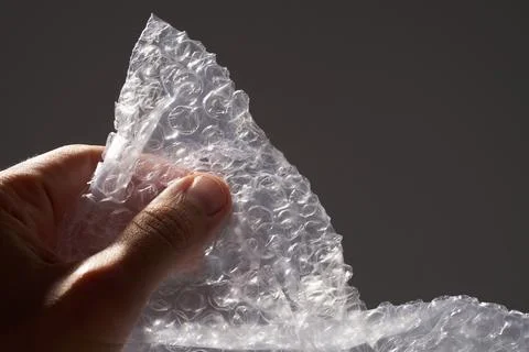 A man's hand bursts bubbles from the bubble wrap. Stock Photos