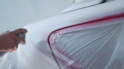 A mans hand with a can of spray paint applies airbrushing to a car body, close Stock Footage 307205519