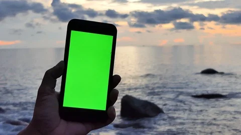 The man's hand caught the green screen phone on the beach at sunset. Vídeo Stock 118520725