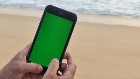 The man's hand caught the green screen phone on the beach 库存影片 118998318