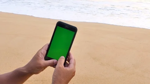 The man's hand caught the green screen phone on the beach 库存影片 119403399
