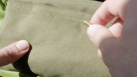 Man's hand is checked on a green fabric durability. A sharp screw does not leave Stock Footage 76301376