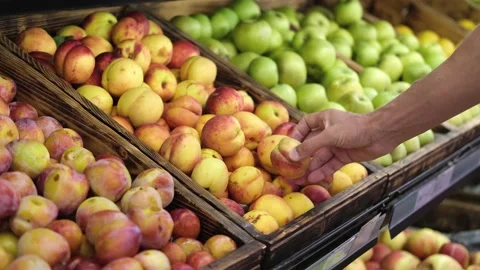 A man's hand chooses a nectarine on a store counter. Stock Footage 208337055