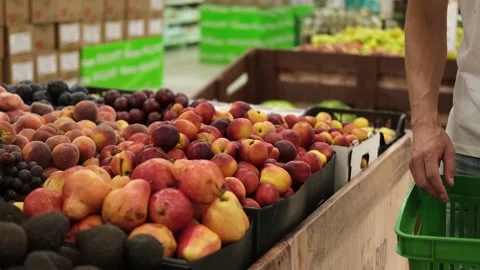 A man's hand chooses a nectarine on a store counter. Stock Footage 227944808