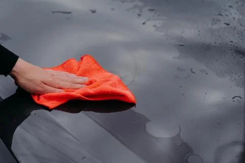 Mans hand cleans surface of black car with microfiber cloth. Maintenance and  Stock Photos
