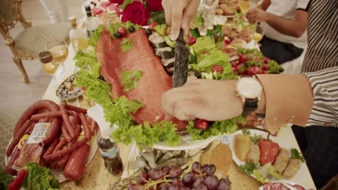 A man's hand with a clock cuts fillets of red fish with a knife on festive table Stockbeeldmateriaal 251556133