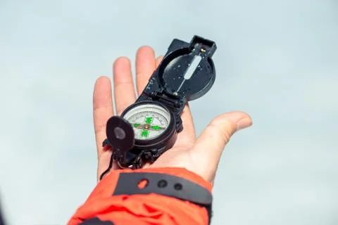 Man's hand close-up with a compass on white snow background Stock Photos