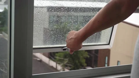 The man's hand closed the window because it was raining. Vidéo 180961577