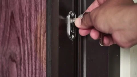 A man's hand closes the iron-framed wooden door, inserts the key and turns to Video stock 321741213
