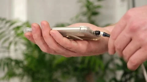 Man's hand connects magnetic cable for charging smartphone Stock Footage 242298577